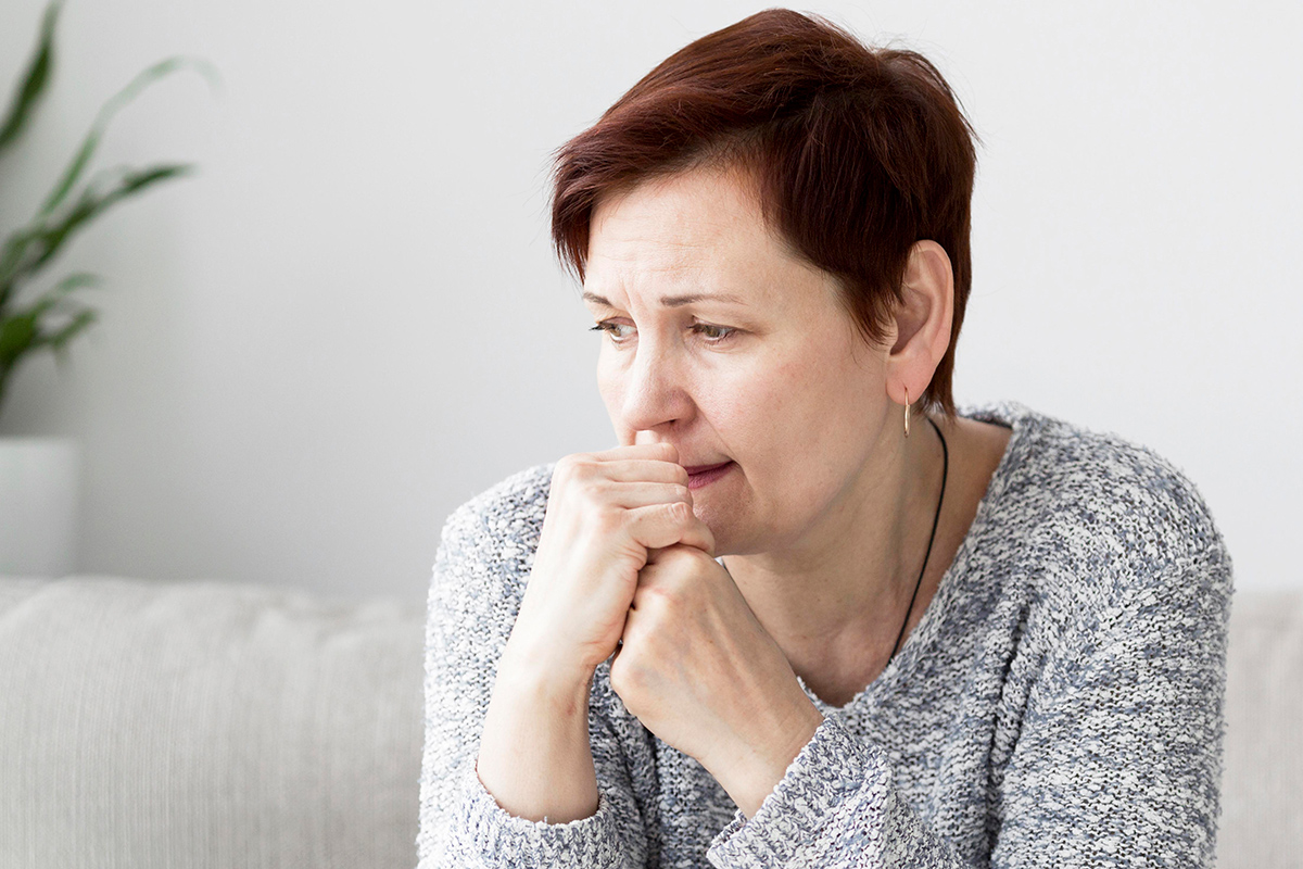 A woman sad with her hand to her mouth and looking off to the side