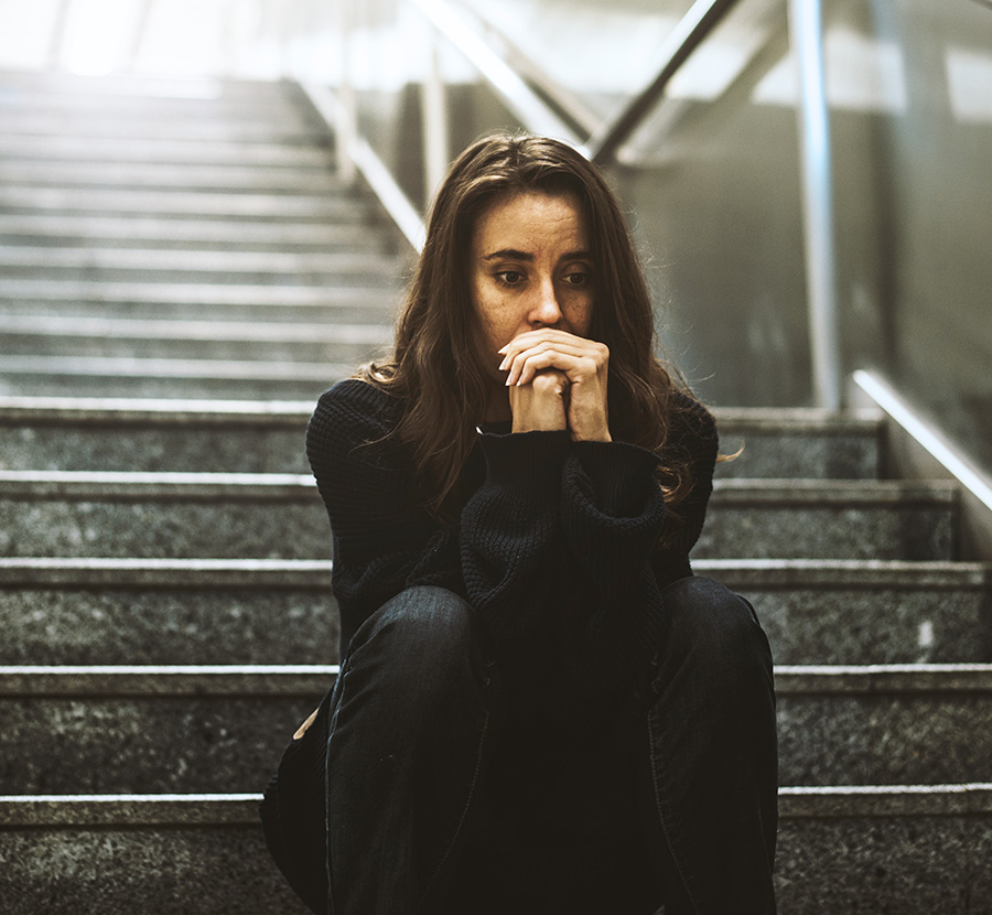 A woman sitting on the stairs coping with PTSD