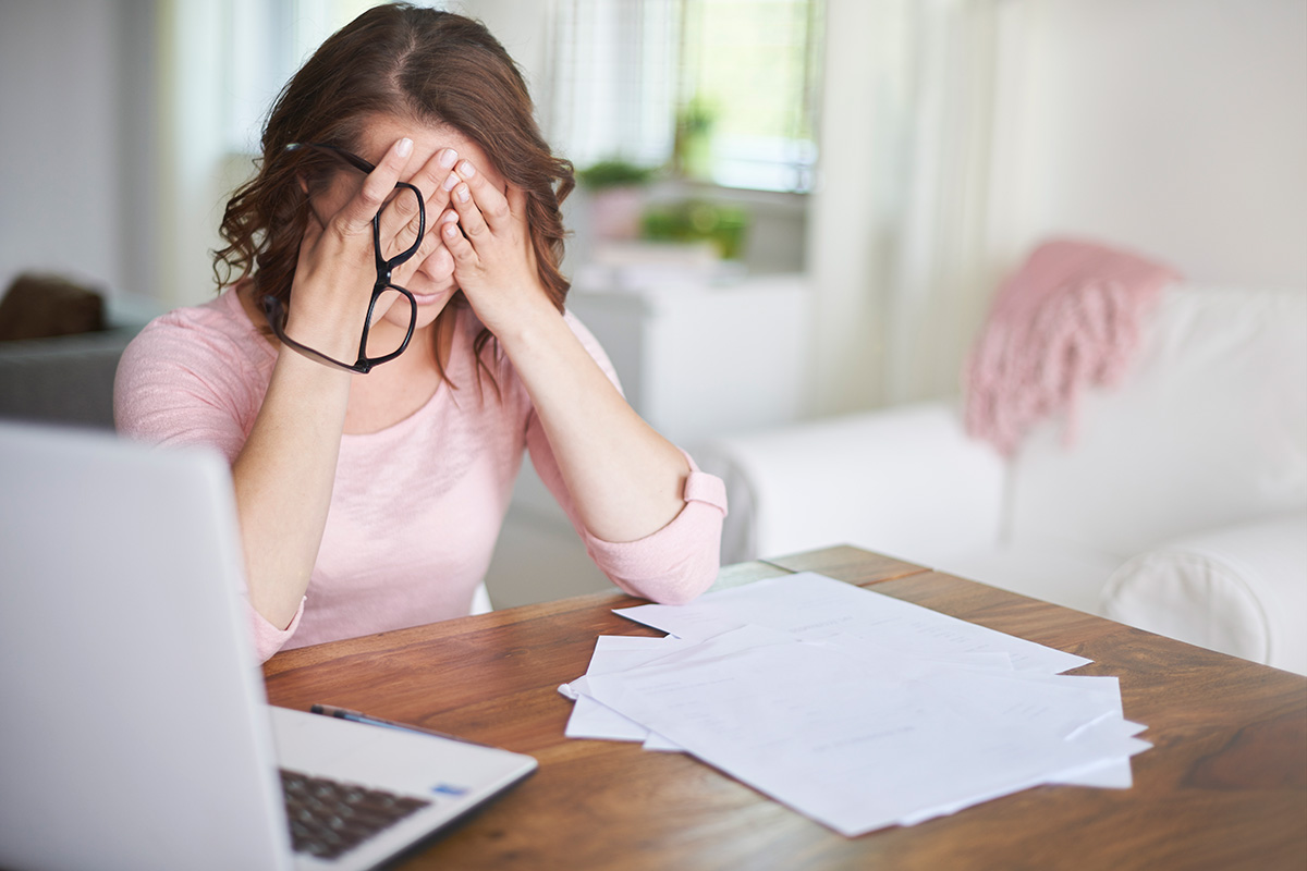 A busy businesswoman with anxiety holding her face in her hand working home office