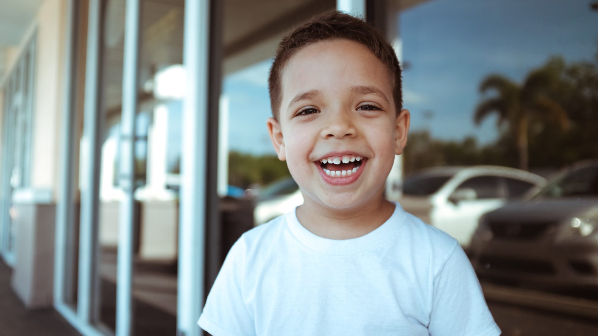 happy young spanish child smiling in front of storefront