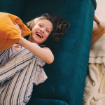 Child laying on a mat holding a pillow.