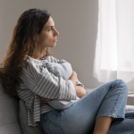 Woman sitting, hugging a pillow, coping with major depressive disorder.