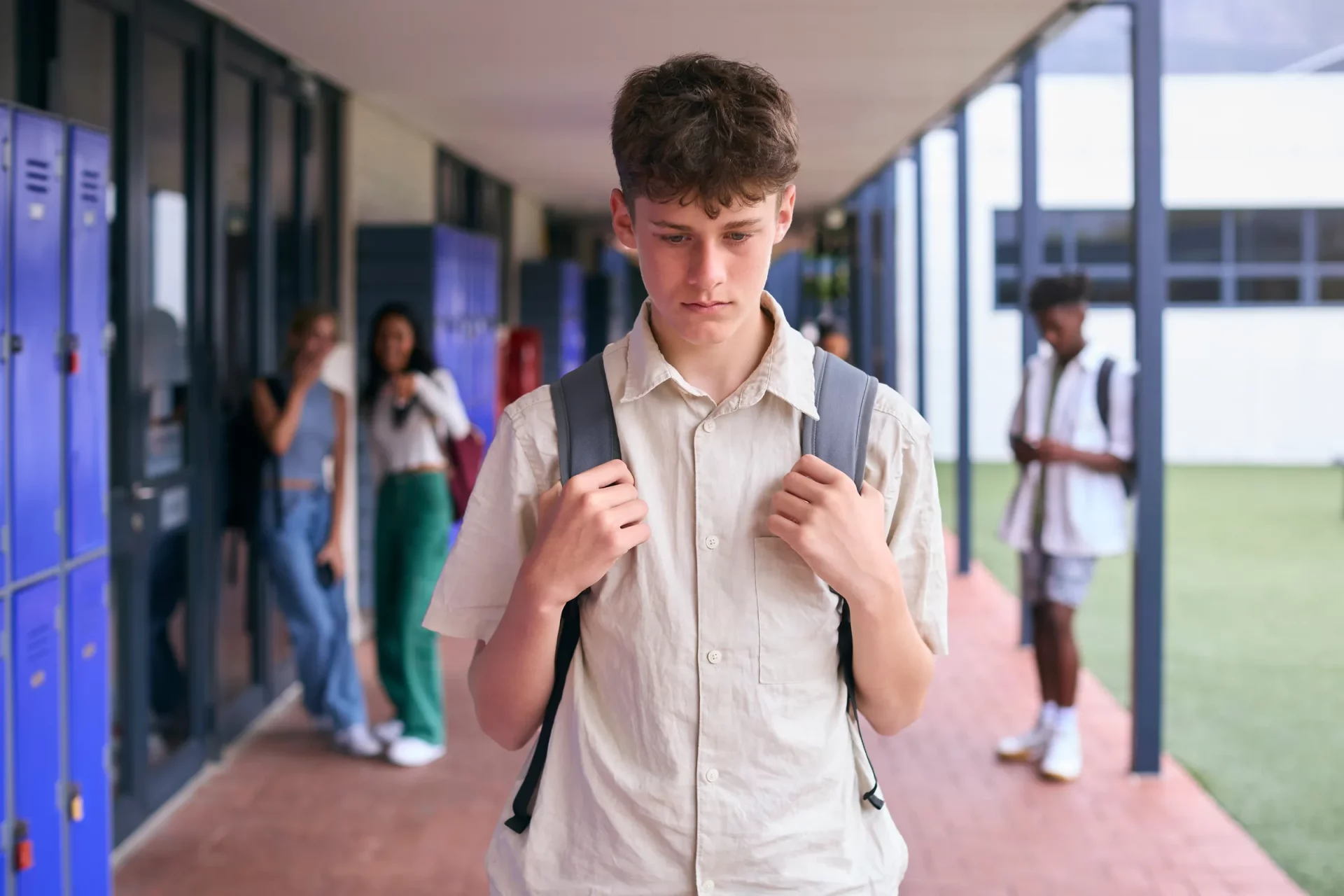 boy looking down in hallway of school